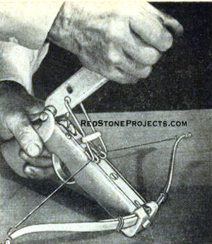 Figure 1. Goat's Foot cocks pistol crossbow - hooks on channel sides, draws back bowstring, sets it in wheel.