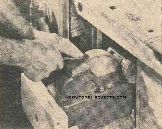 Figure 8. Grinder – wet-type in this case – pulls out from the bench ready for use. Oilstone is stored behind the grinder on the shelf.