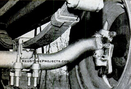 Axle and springs were salvaged from a 1936 Plymouth and spring reduced to four leaves. Hub to fit VW wheels was made from 1/2 in. sheet steel. VW rims and tires cost builder $24.
